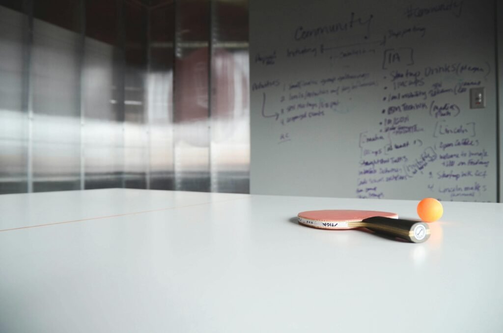 Close-up of ping pong paddle and ball on office table, creative workspace.