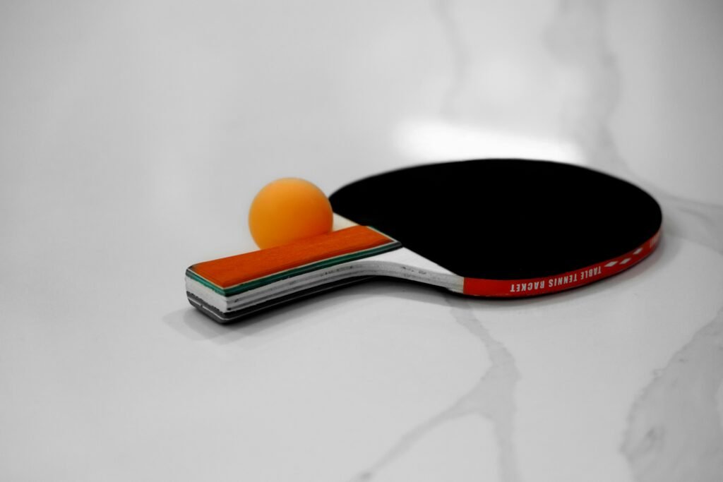 Close-up of a table tennis racket and orange ball on a white background.